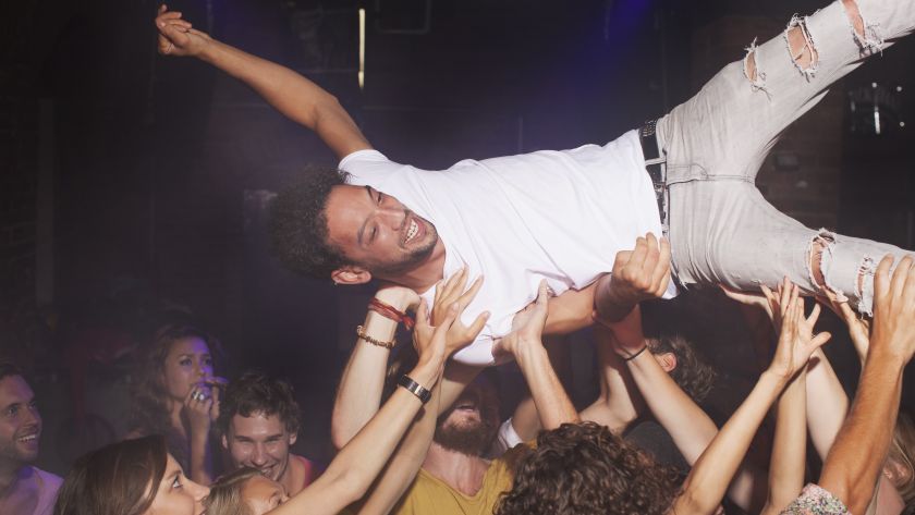 Group of people lifting man in club