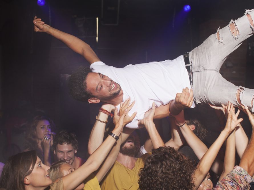 Group of people lifting man in club